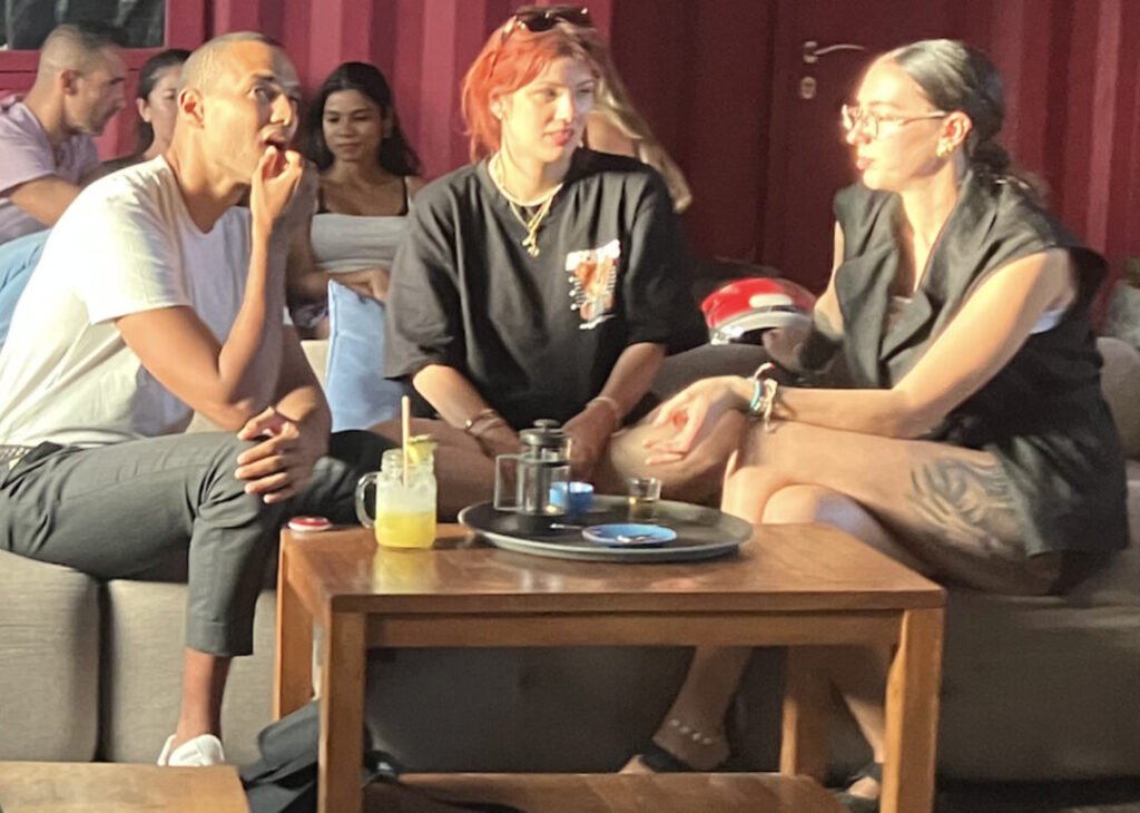 Three individuals seated at a table, each using a laptop, engaged in a collaborative work session.